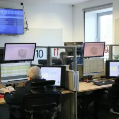 Operatorzy 112 pracują w centrum dowodzenia, monitorując sytuację na mapach i danych.