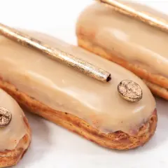 Délicieux éclairs au café, parfaits pour savoir quoi faire avec de la crème pâtissière. Ils sont décorés de grains de café dorés et d'une touche de paillettes.