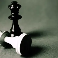Czarna królowa stoi nad pokonaną białą figurą. To obraz strategii i triki szachowe.
