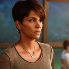 Halle Berry w filmie, zamyślona, w tle niewyraźne dziecko.