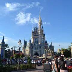 Tłum ludzi spaceruje przed zamkiem w Disneylandzie, gdzie marzenia stają się rzeczywistością.