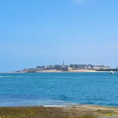 Une personne admire la vue sur la ville fortifiée, une belle journée pour une randonnée le long de la Rance.