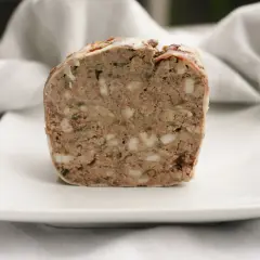 En bit rustik lantpaté med synliga bitar av fett och örter, perfekt för ett lantpaté recept.
