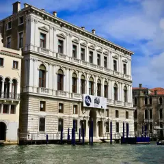 Le **Palazzo Grassi** à Venise, majestueux édifice blanc, se reflète dans le Grand Canal. Une exposition Irving Penn y est annoncée.