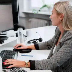 Kobieta w biurze pracuje przy komputerze, skupiona na zadaniach. To jej praca z norweskim, która wymaga precyzji i zaangażowania.