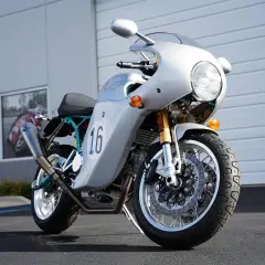 Moto Ducati plateada con el número 16, inspirada en el estilo de Paul Smart, lista para la carretera.