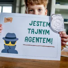 Chłopiec trzyma kartkę z napisem "Jestem tajnym agentem!" i rysunkiem szpiega. Idealne do gry szpiegowskie.