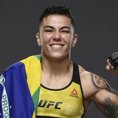 Jessica Andrade, MMA-fighter, ler glatt med Brasiliens flagga över axeln och en boxningshandske på sin högra hand.