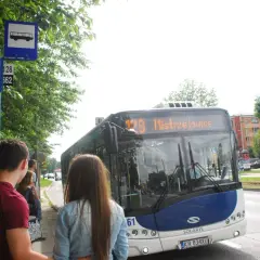 Autobus MPK na przystanku z pasażerami, znak z ikoną autobusu.