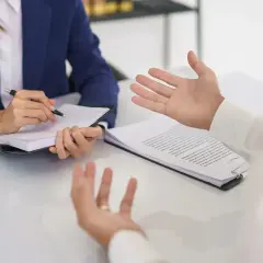 Rozmowa o warunkach zatrudnienia, gdzie jawność wynagrodzeń jest kluczowa. Kobieta notuje, mężczyzna gestykuluje.