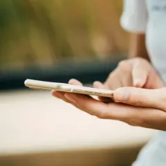 Dłonie trzymające złoty telefon. Zastanawiasz się, jak wyczyścić telefon? Oto praktyczny poradnik.