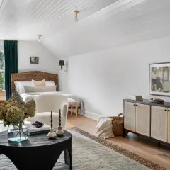 A cozy bedroom with a mix of dark and light wood furniture, featuring rattan headboards, a dark wood cabinet, and light wood nightstands.