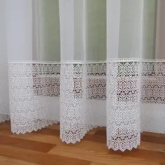 Białe firanki z koronkowym dołem, gdzie widać ażurowy wzór gipiury.