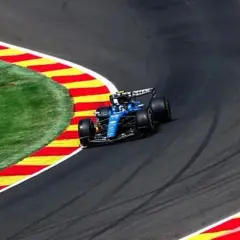 Un coche azul de Fórmula 1 toma una curva cerrada en la pista, con la hierba y las rayas rojas y amarillas de la escapatoria a su lado. La clasificación de Fórmula 1 hoy promete emoción.