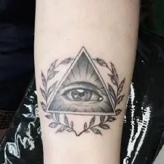 Oko proroka tatuaz w trójkącie otoczone gałązkami. Symbol czujności i wiedzy.