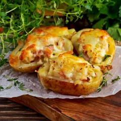 Zapiekane ziemniaki z serem i boczkiem, podane z ziołami. Czy pieczone ziemniaki są lekkostrawne? Tak, jeśli są dobrze przygotowane.