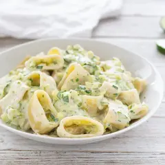 Piatto di pasta robiola e zucchine, cremoso e invitante, con pezzi di zucchine fresche e erbe aromatiche.