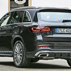 Ciemnoszary Mercedes-Benz GLC 300e z eleganckimi światłami LED i chromowanymi końcówkami wydechu, zaparkowany przed budynkiem z oknem.