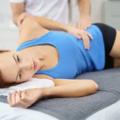 Fizjoterapeuta masuje kobietę z zapaleniem kaletki, łagodząc ból.