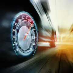 Prędkościomierz pokazuje ponad 180 km/h. Samochód pędzi drogą ekspresową, rozmazując krajobraz.