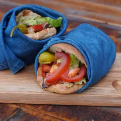 Två kebab i ugn, inslagna i jeans, serveras på en träbricka.