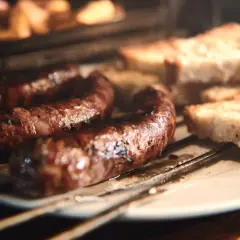 Figatelli grillés au four, accompagnés de tranches de pain croustillant. Une recette simple et savoureuse.