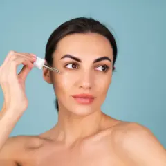 Kvinnan applicerar serum med retinol ansikte.