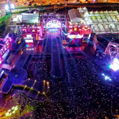 Widok z lotu ptaka na nocny koncert z tłumem i oświetloną sceną.
