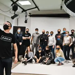 Grupa uczestników kursów foto w studiu, pozuje do wspólnego zdjęcia. Jeden z nich robi selfie.