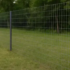 Solidne słupki i naciąganie siatki leśnej tworzą trwałe ogrodzenie. W tle zielony las i trawnik.