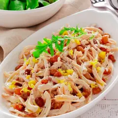 Insalata di pollo sfiziosa con uvetta e scorza di limone, guarnita con rucola fresca.