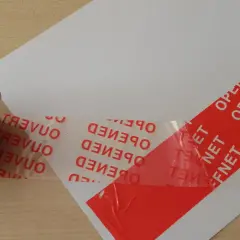 Czerwona taśma konturowa z napisem "OPENED" i "OUVERT" zabezpiecza biały papier.