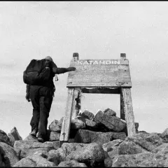 A lone hiker reaches the summit of Katahdin, a testament to perseverance in this striking fine art photography.