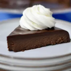 En bit fransk chokladtårta med en virvel av vispad grädde på en tallrik.