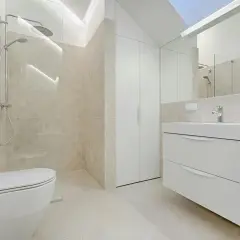 Baño moderno con ducha, inodoro y mueble de lavabo flotante. La decoración de baños pequeños se inspira en la luz y los tonos neutros.
