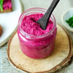 Glas mit cremigem, veganem Rote Bete Aufstrich, daneben Brot mit Aufstrich und Schnittlauch.