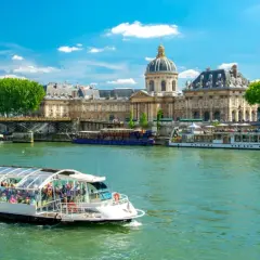 Bateau touristique sur la Seine, avec l'Institut de France et un pont en arrière-plan. Une belle journée pour une visite Paris Seine.