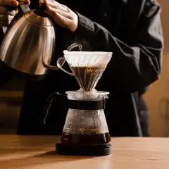 Person gießt heißes Wasser über Kaffeepulver in einem Filter. Die richtige filterkaffee temperatur ist entscheidend für den Geschmack.
