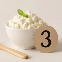 Ricotta di mucca fresca in ciotola, con cucchiaio e numero 3. Un alimento leggero, ma attenzione al colesterolo!