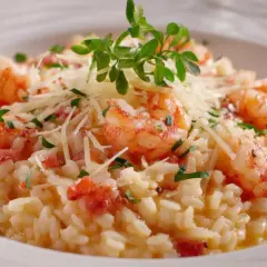 Un crémeux risotto au gambas, garni de parmesan râpé et d'une touche de verdure fraîche. Un délice pour les yeux et les papilles.