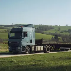 Ciężarówka z naczepą na tle zielonych wzgórz. Zastanawiasz się, ile wazy ciągnik? Ten model jest gotowy do drogi.