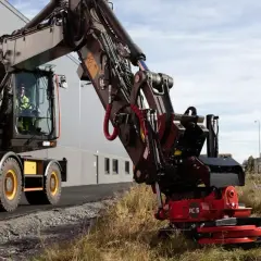 Koparka z zamontowaną głowicą obrotową do koparki, gotowa do pracy przy budowie drogi.