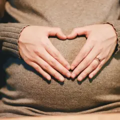 Dłonie tworzą serce na brzuchu w czasie ciąży.