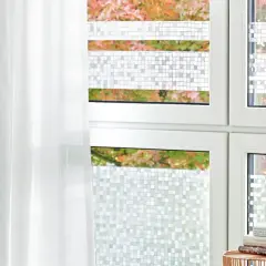 Fenster mit statischer Fensterfolie im Mosaikmuster, die Privatsphäre schafft. Ein weißer Vorhang hängt daneben.