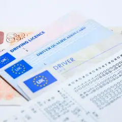 Brytyjskie prawo jazdy, karta kwalifikacji kierowcy i paragon obok banknotu 10 funtów. Wniosek o kartę kierowcy.