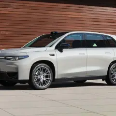 Elegante auto elettrica Leapmotor C10 color argento metallizzato, con un design moderno e linee aerodinamiche, parcheggiata davanti a una parete di legno.