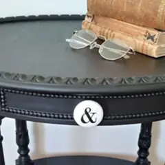 Come trasformare un vecchio comodino in un pezzo d'arredo chic: un tavolino nero con pomello a "&" e libri antichi.