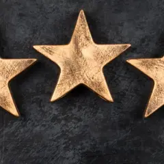 Trzy złote gwiazdki, symbolizujące wysoki standard, jak gwiazdki w hotelach, na ciemnym tle.