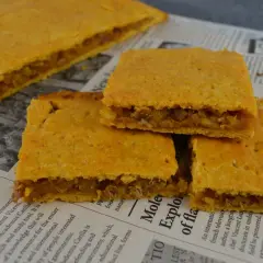 Coca amb tonyina, un delicioso pastel salado relleno de atún y cebolla, servido sobre un periódico.
