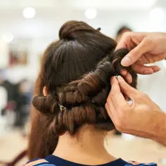 Hårstylist hjälper till att rulla håret på spolar för att skapa volym och lockar.